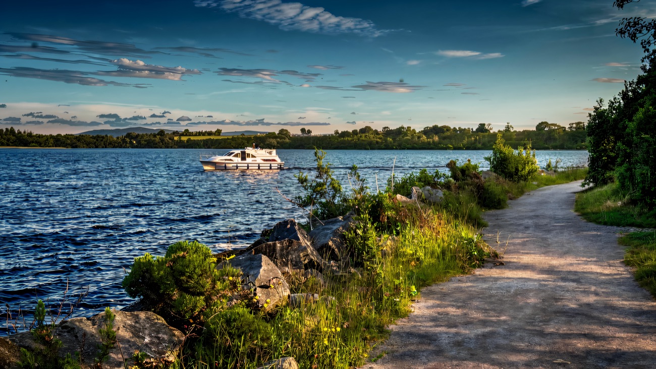The lakeside path skirting Lower Lough Erne with a cruiser drifting by