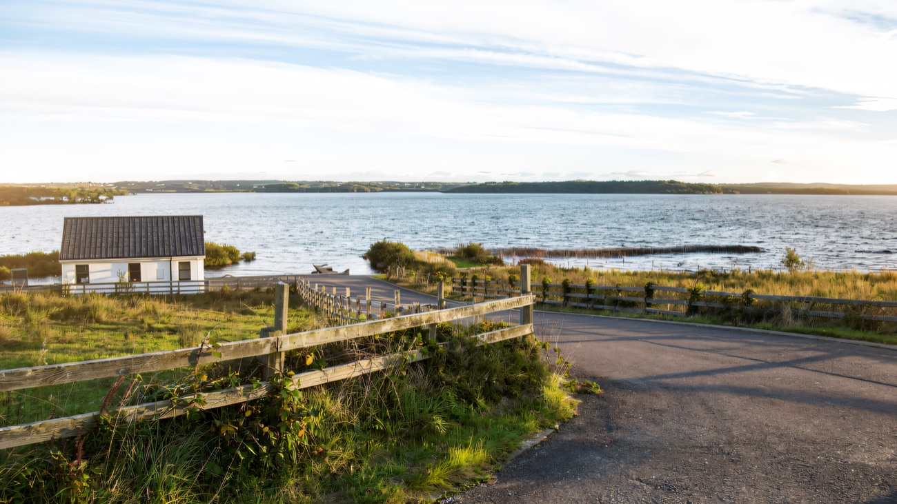 A quiet lane bending past a lakeside cottage on the loop