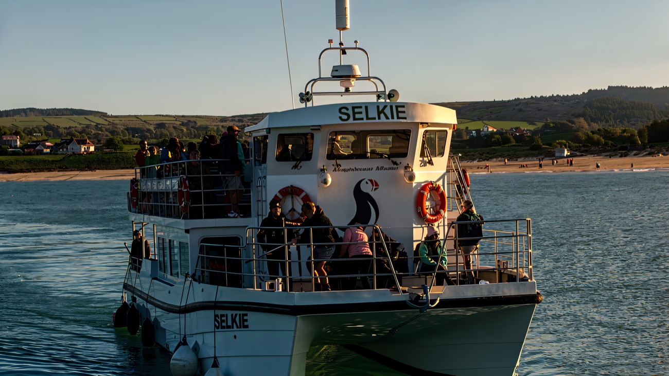 The Selkie comes in off a wide sandy beach, passengers gathered on deck