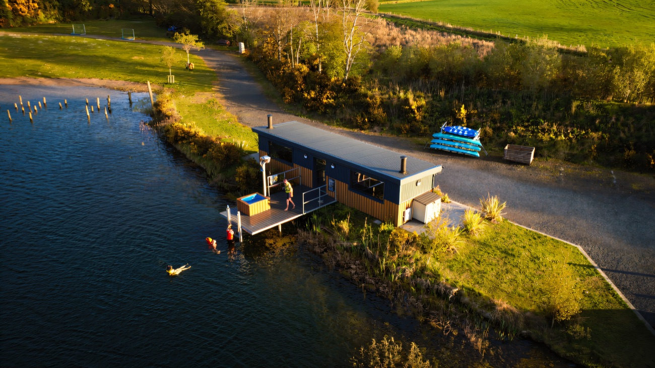 The lakeside cabin and hot tub with kayaks lined up on the bank