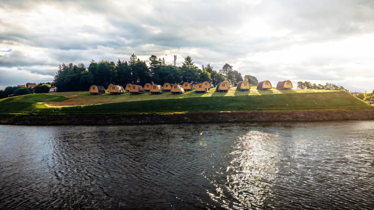 Glamping pods perched on the green above the water