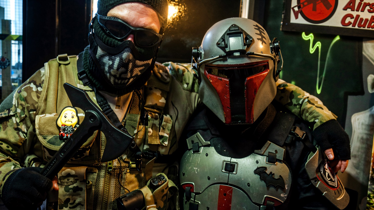 Two fully masked players in kit beside the Lagan Airsoft Club sign at the entrance