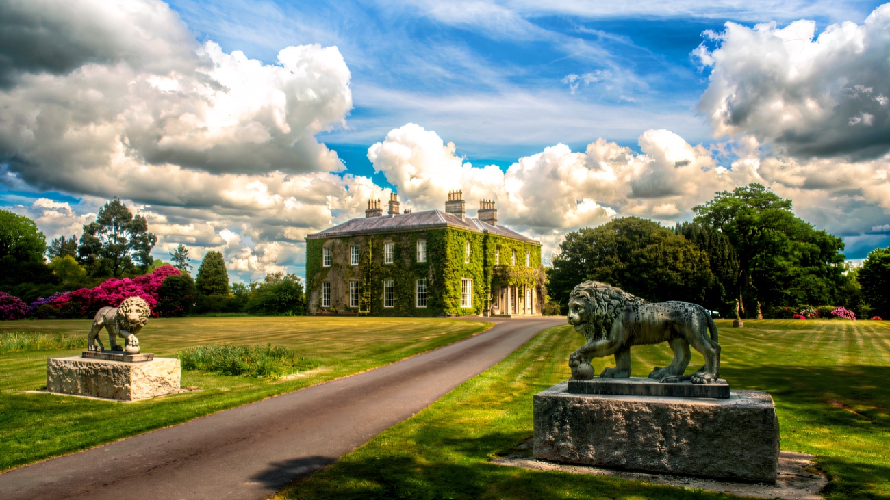 The Georgian house across green parkland, flanked by stone lion statues