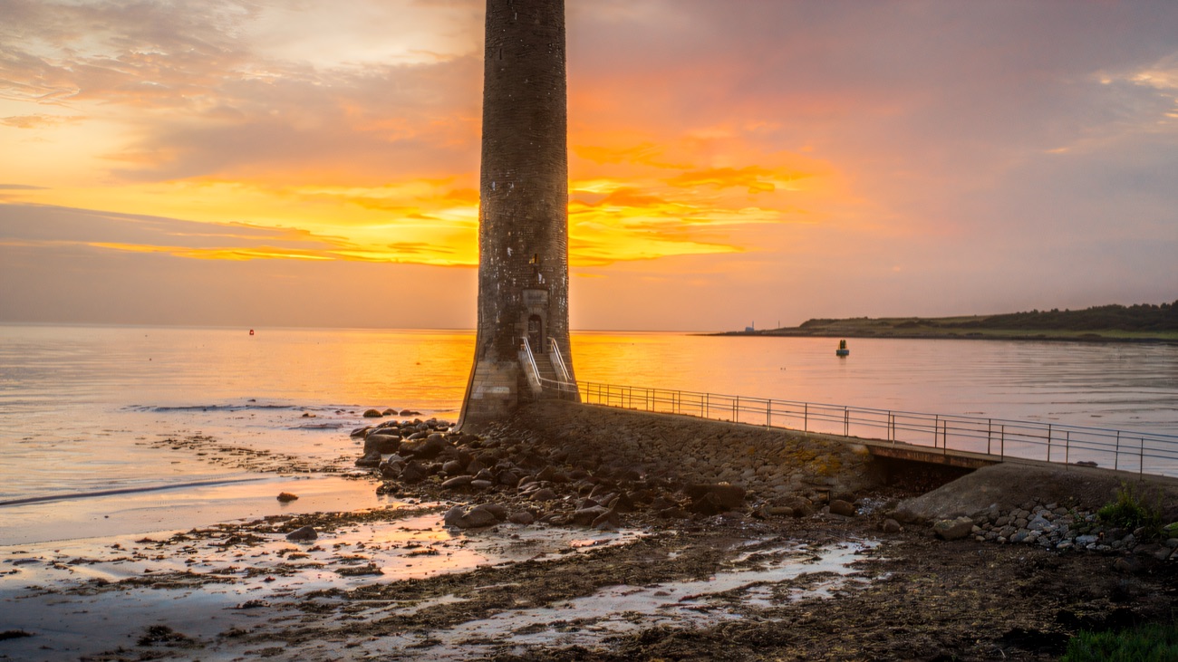 The tower silhouetted against a golden sunset over the sand