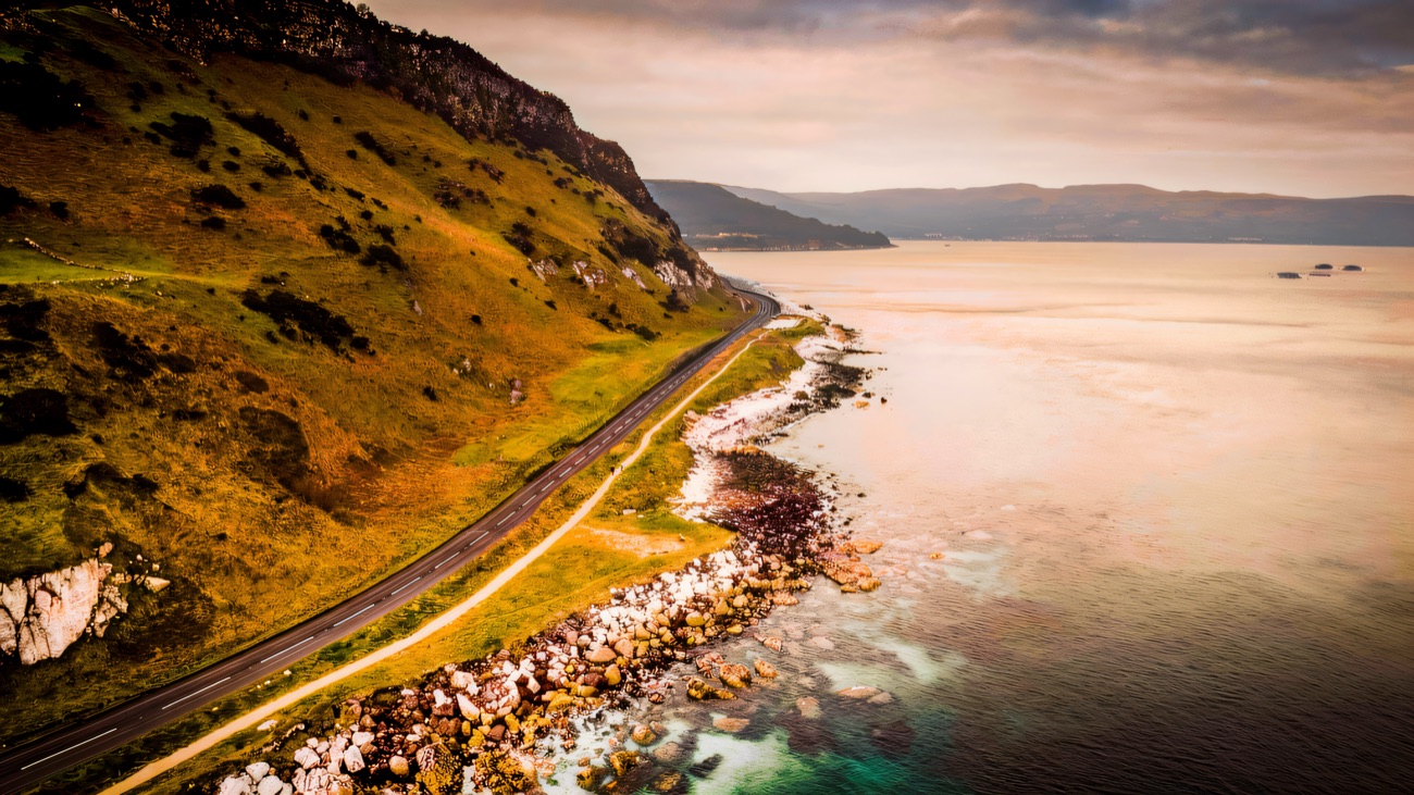 The Antrim Coast Road hugging the cliffs above turquoise water