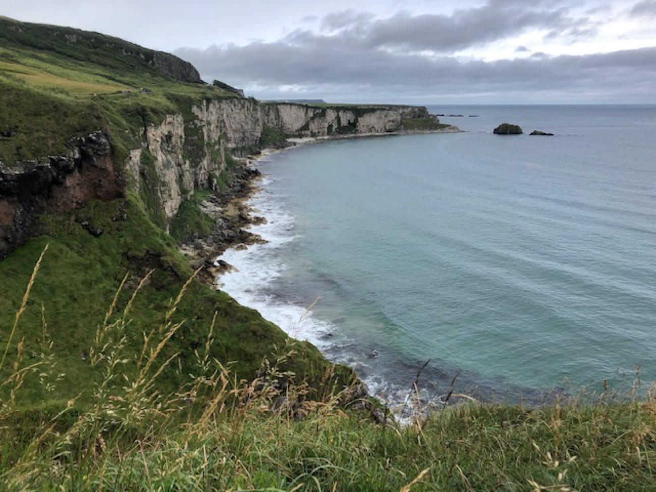 The tall white limestone cliffs of Larrybane curving round a bay under a moody sky