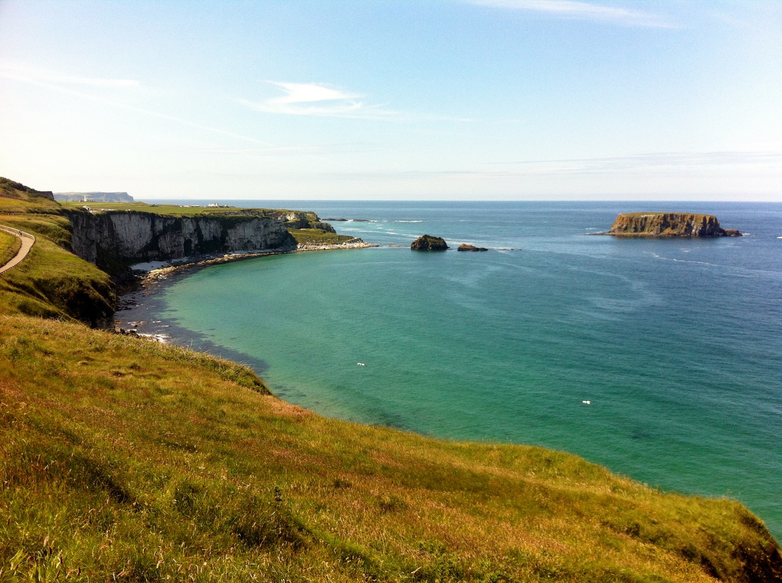 Larrybane's white cliffs and grassy headland above a turquoise bay with Sheep Island out to sea