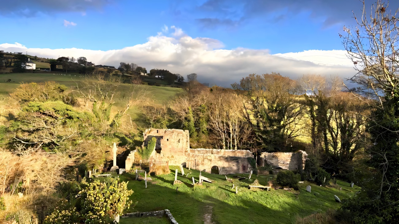 The ruins in dramatic light, the glen and coast opening out behind.