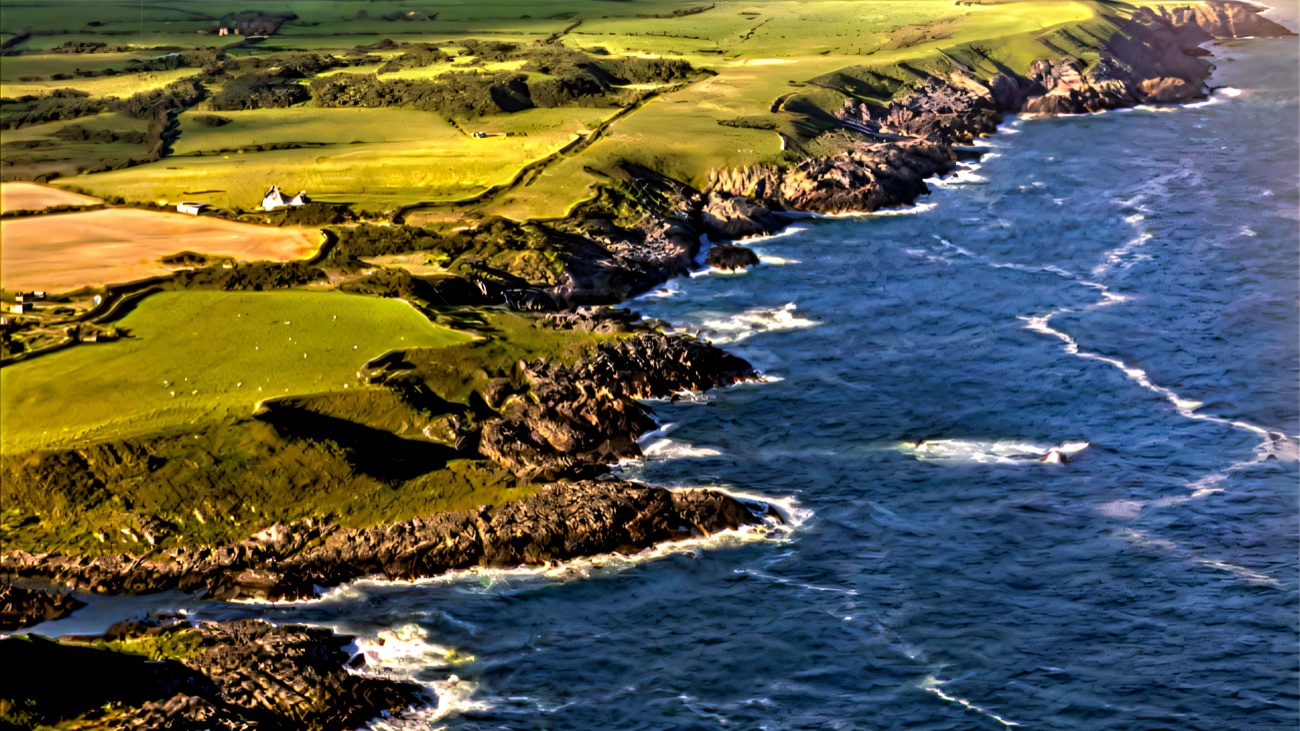 An aerial of the rugged coastline, patchwork fields meeting the rocky shore