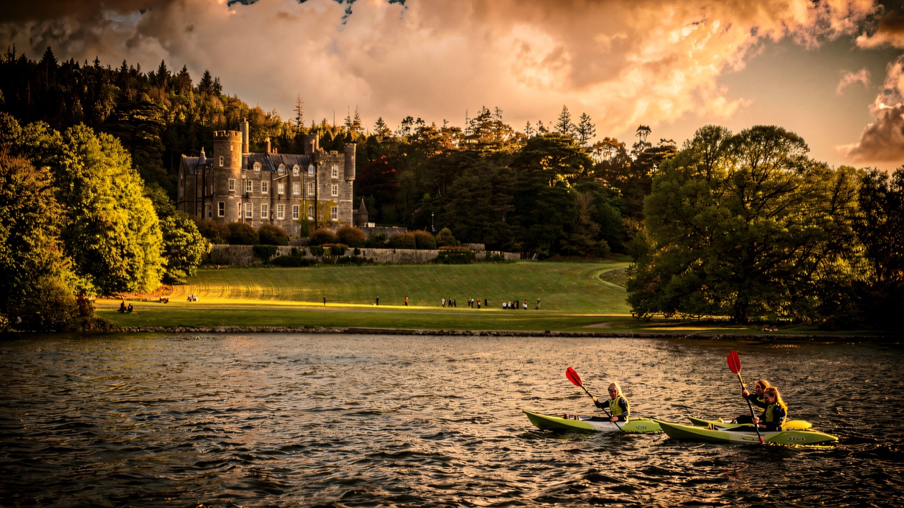 Kayaks gliding across the lake with Castlewellan Castle rising behind the trees