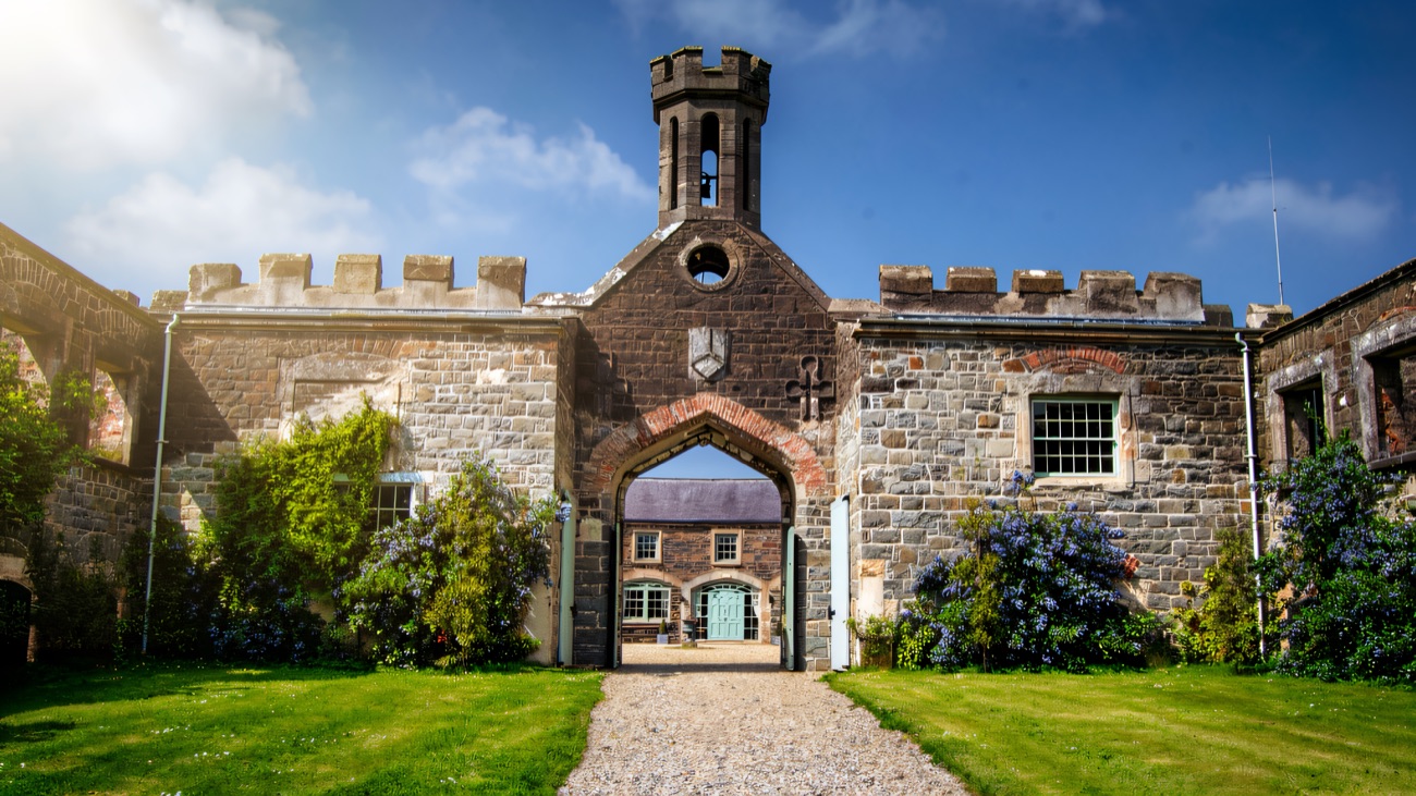 The castle courtyard front — a stone archway under the clock tower, framed by flowers