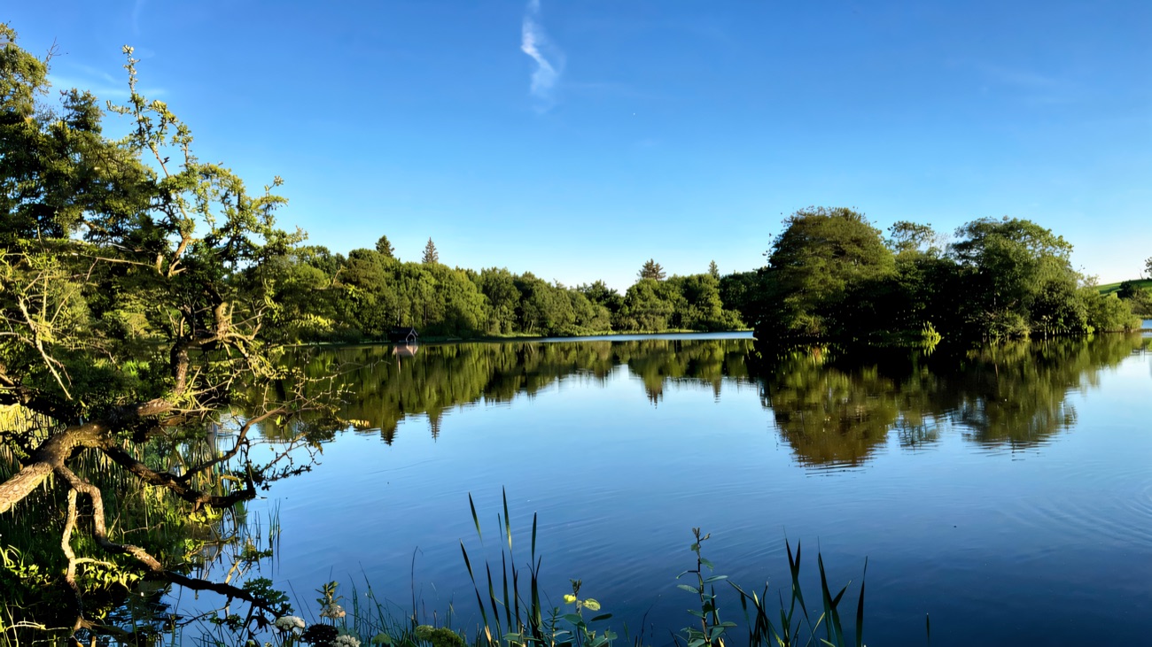 Lissanoure Lake, still and mirror-calm under a clear blue sky