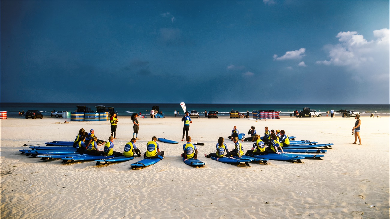 Lesson circle on a vast sun-baked strand, first briefing before the waves