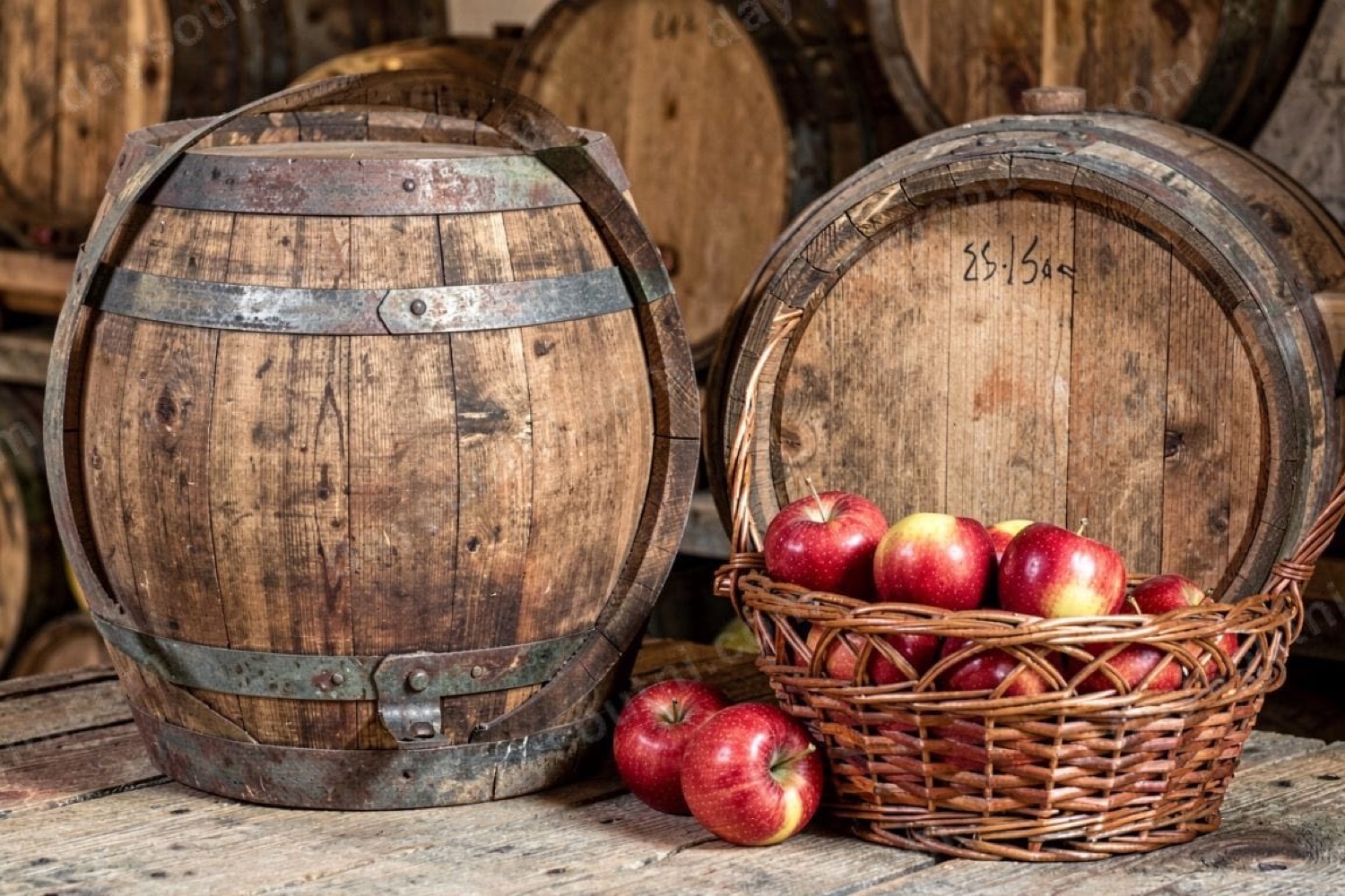 Old wooden cider barrels and a wicker basket of red apples in the cider barn at Long Meadow Cider