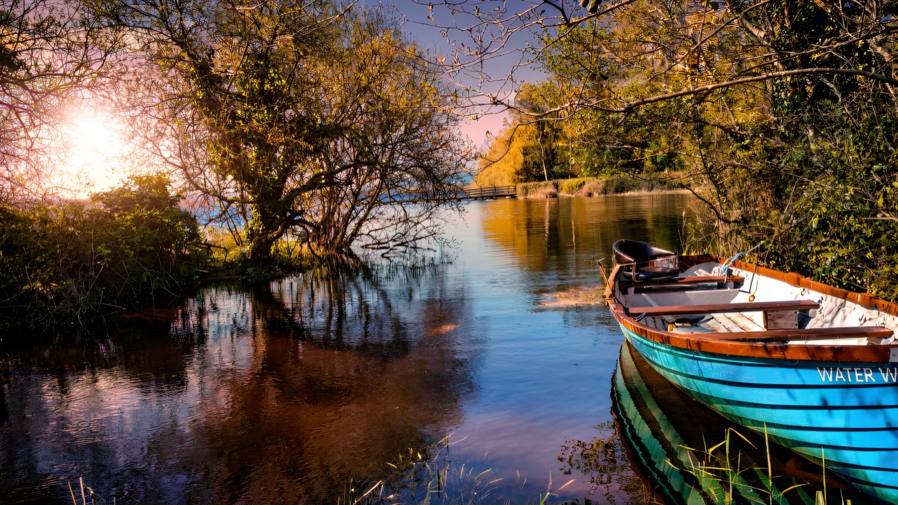 A blue boat moored at a wooded corner of the lough