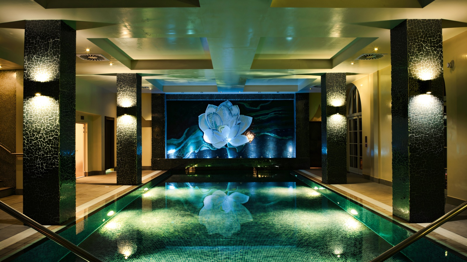 The Thai Spa infinity pool, lit soft green beneath a lotus mosaic.