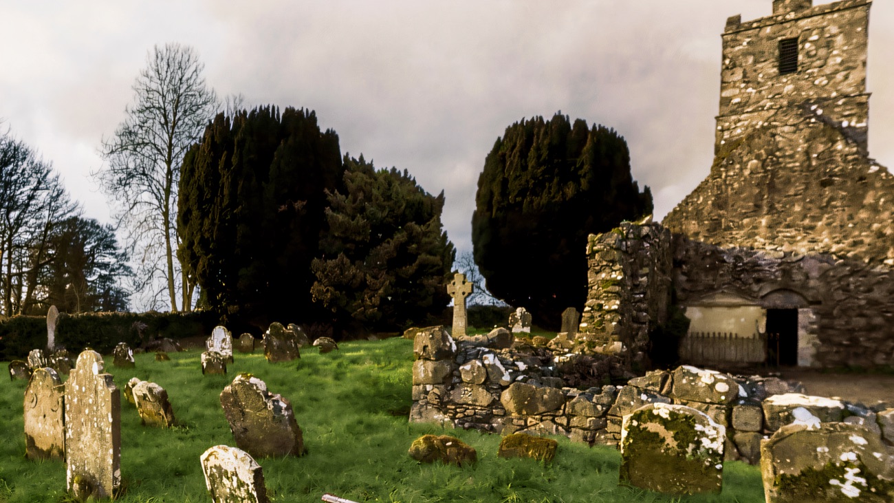 A quieter view across the graveyard, a Celtic cross by the tower.
