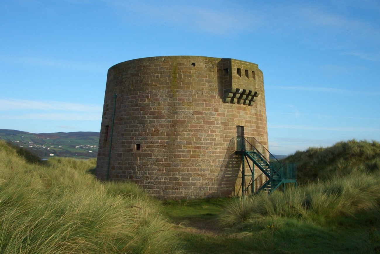 Side view of the well-preserved Magilligan Martello Tower with its metal access stair, set among the dunes above Lough Foyle