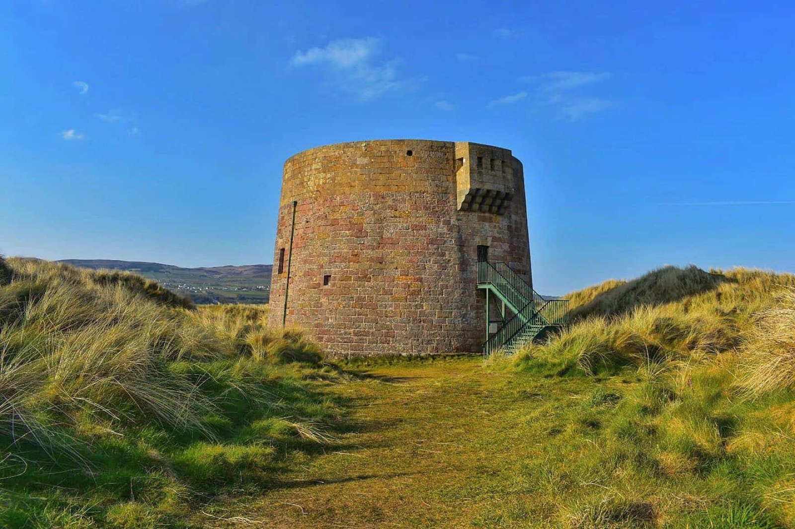 The stone Magilligan Martello Tower standing in the marram-grass dunes at Magilligan Point under a bright blue sky