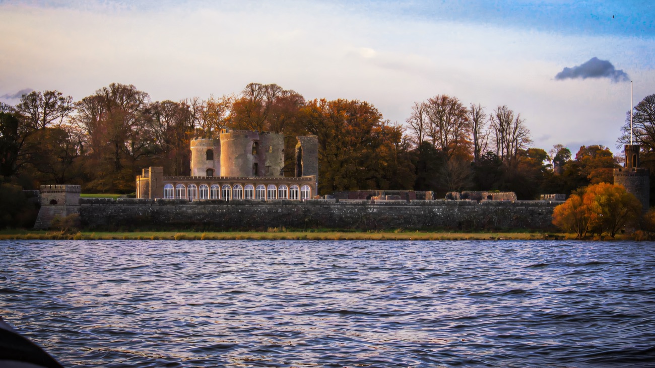 Shane's Castle on the wooded shore, seen from the water.