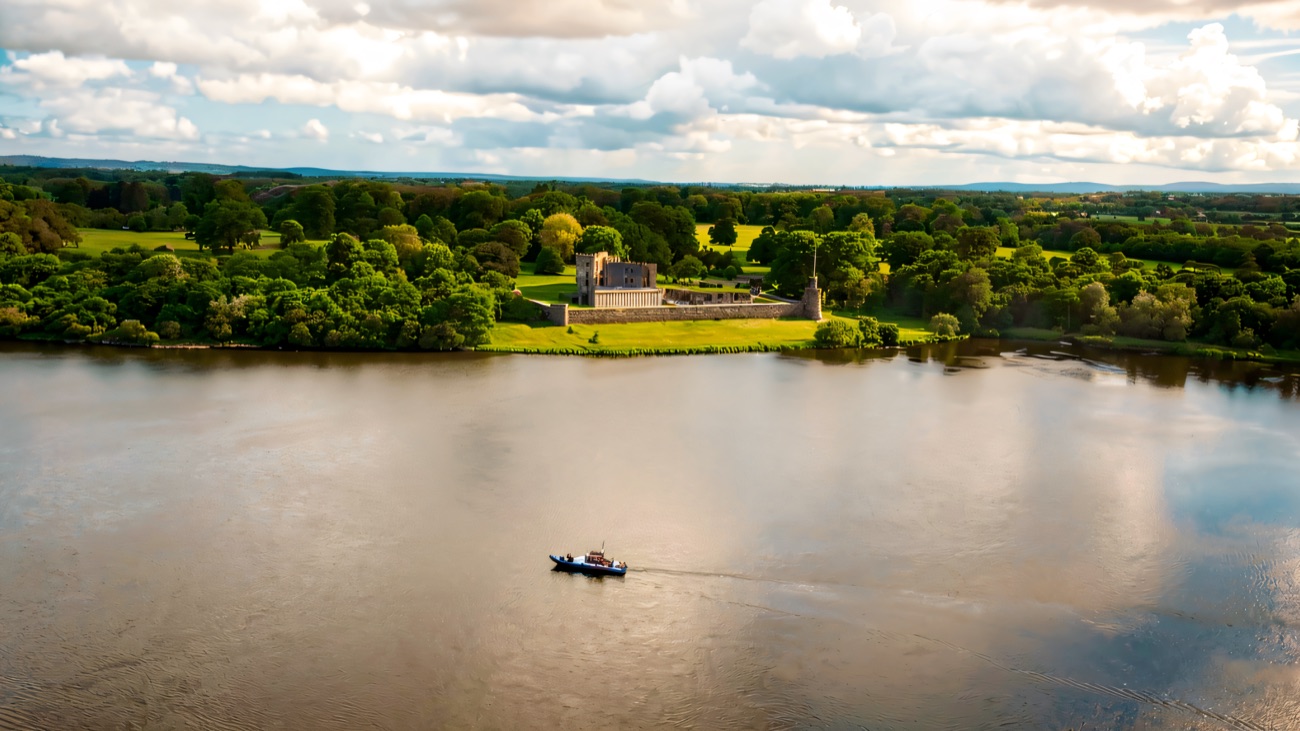A boat crossing the broad lough with Shane's Castle set among the trees.