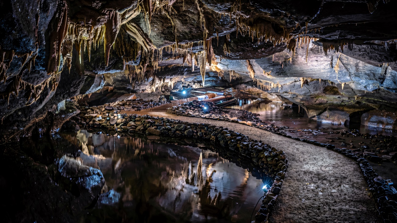 A still black pool mirrors the floodlit cavern
