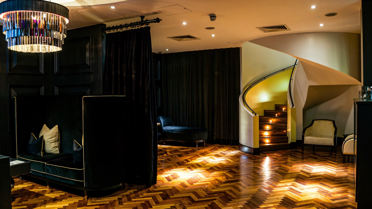 The spa lounge, with its dark panelling, chandelier and a curved staircase.
