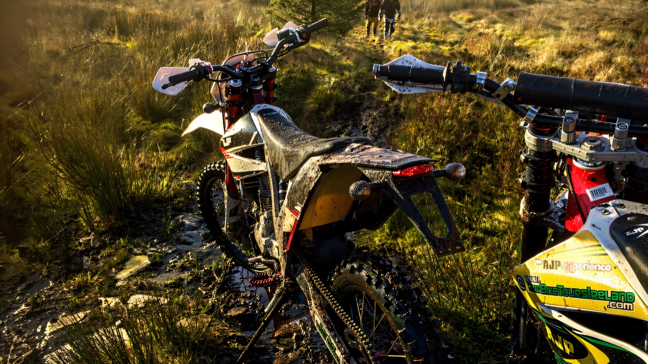 Trail bikes parked up on a boggy forest track