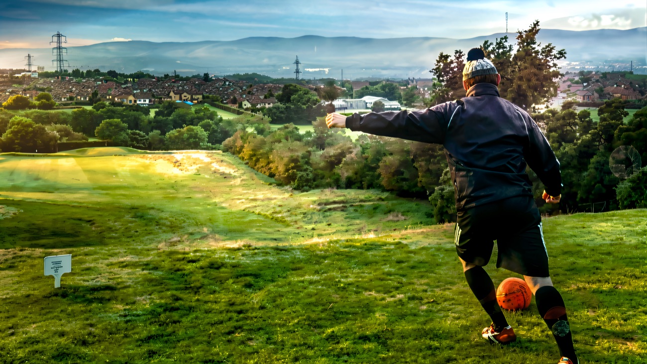 A footgolfer tees off high above Belfast with the city and hills spread out behind