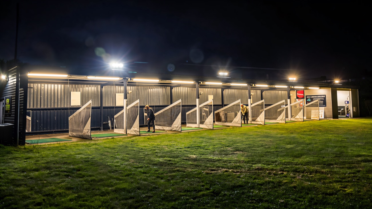 The floodlit driving-range bays light up for evening practice