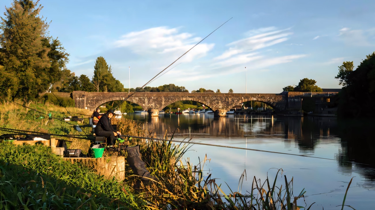 Anglers on the bank looking towards the old stone bridge