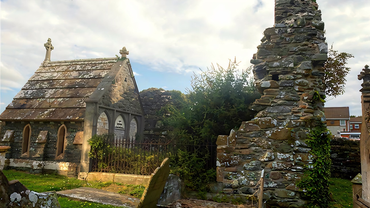 The surviving abbey wall rising among the later graves.