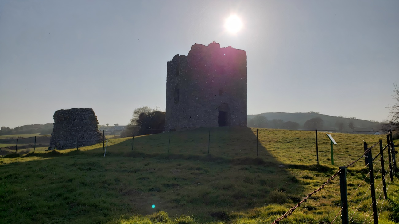 The tower on its low hill, backlit by a low sun over open country.