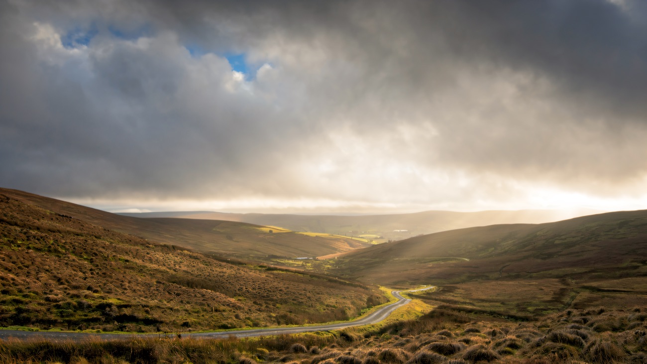A quiet road threading through the rolling Sperrin hills under moody, changing skies.