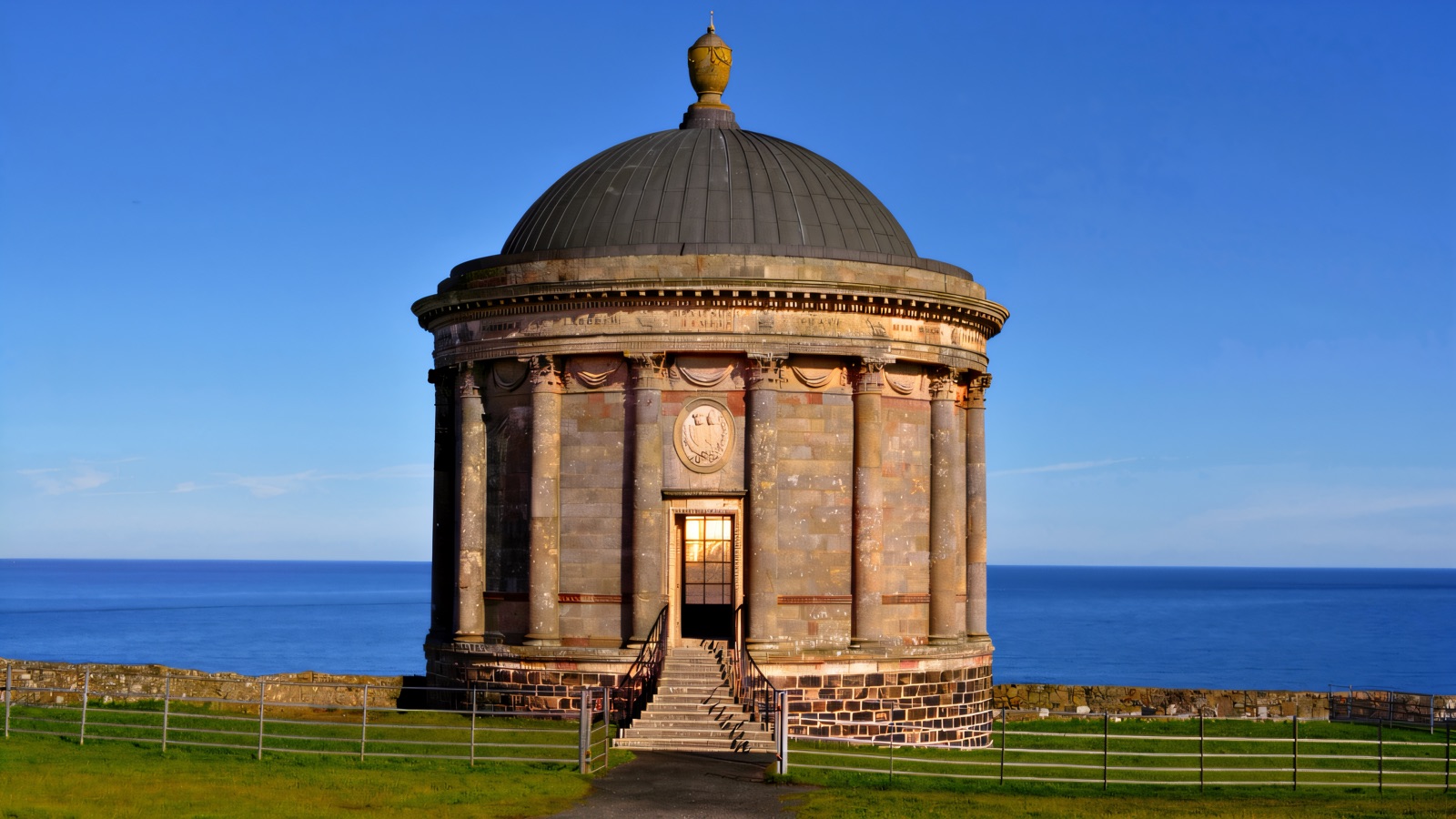 The round domed Mussenden Temple standing against a blue sky above the sea