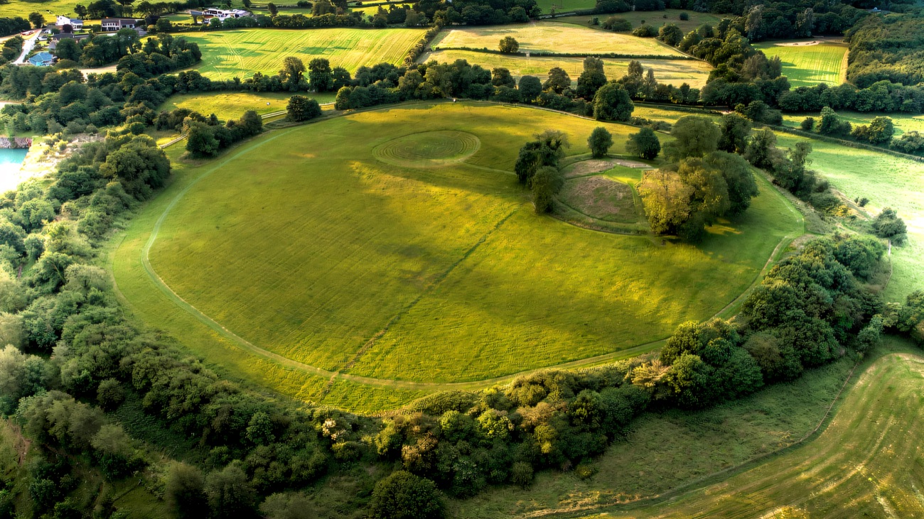 The vast circular earthwork of Emain Macha from the air, its bank and ditch enclosing the central mound.
