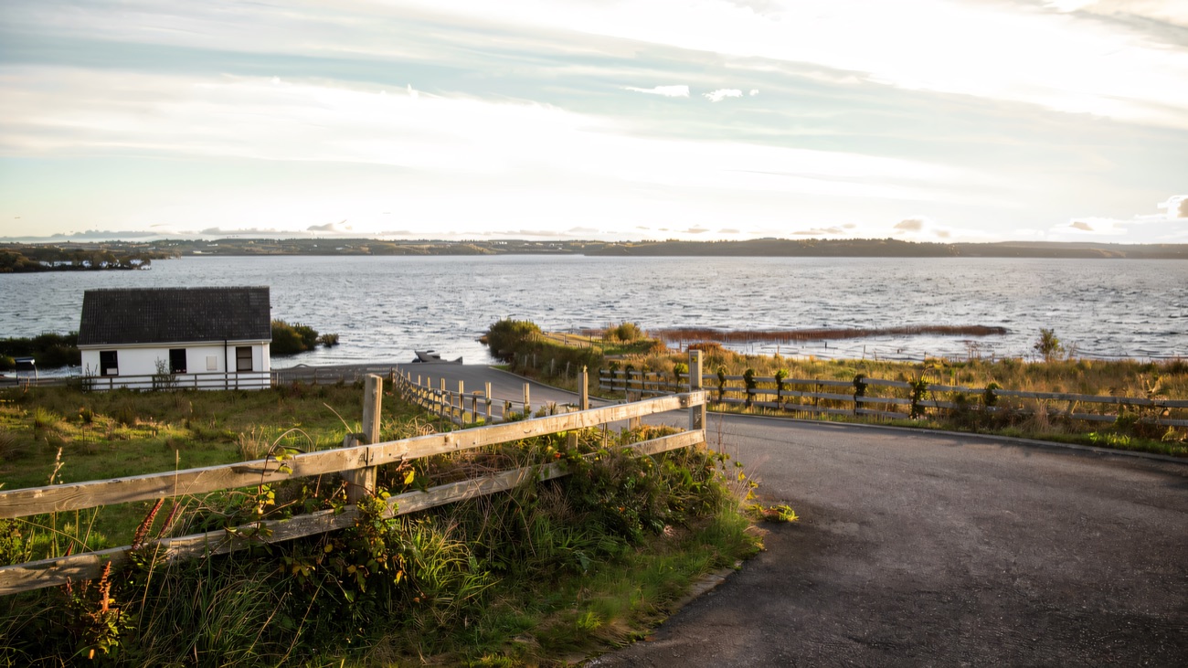 A quiet lough-side lane past a little white fishing hut