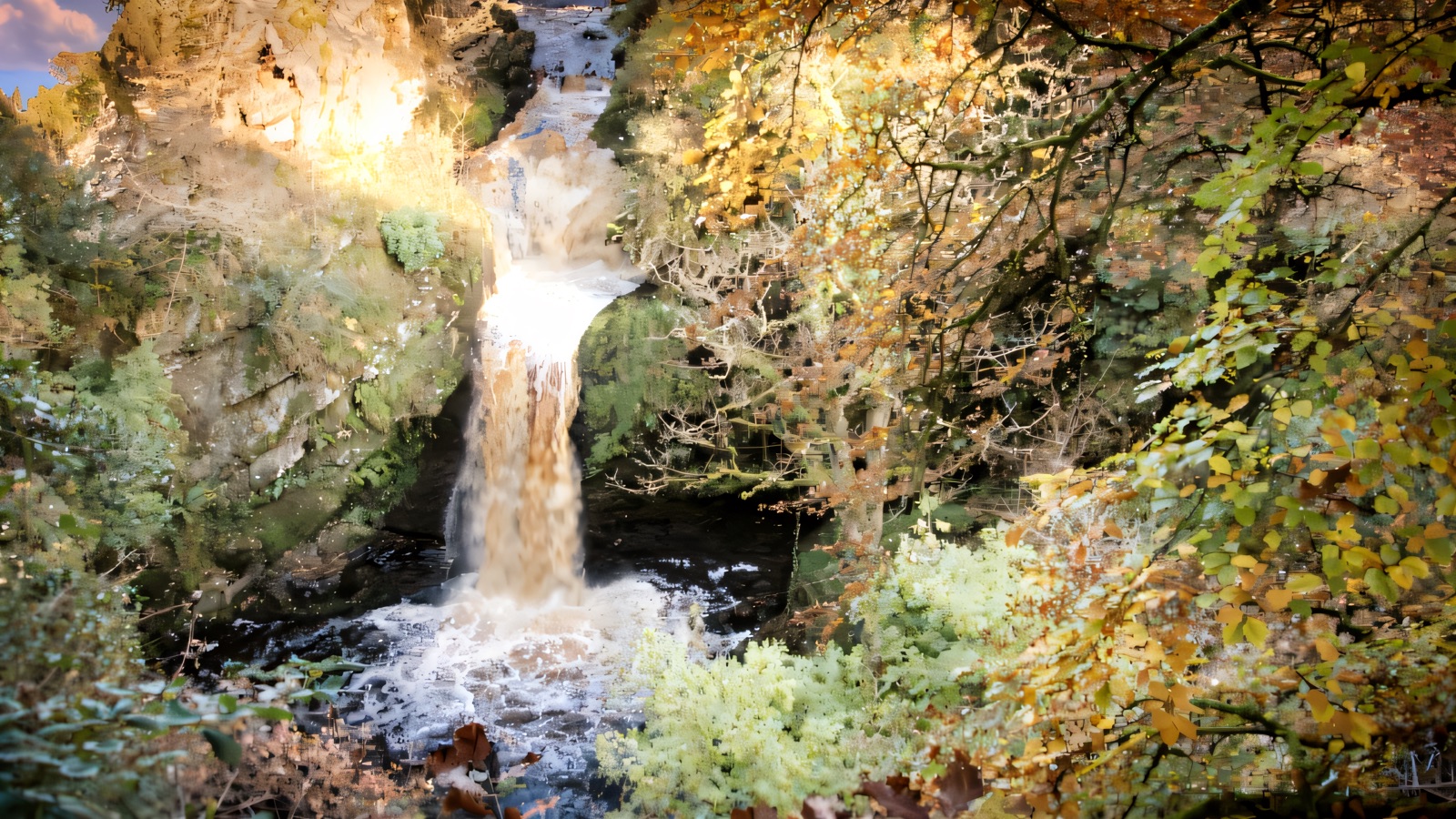 The tall waterfall dropping through the wooded gorge at Ness Country Park in autumn colour