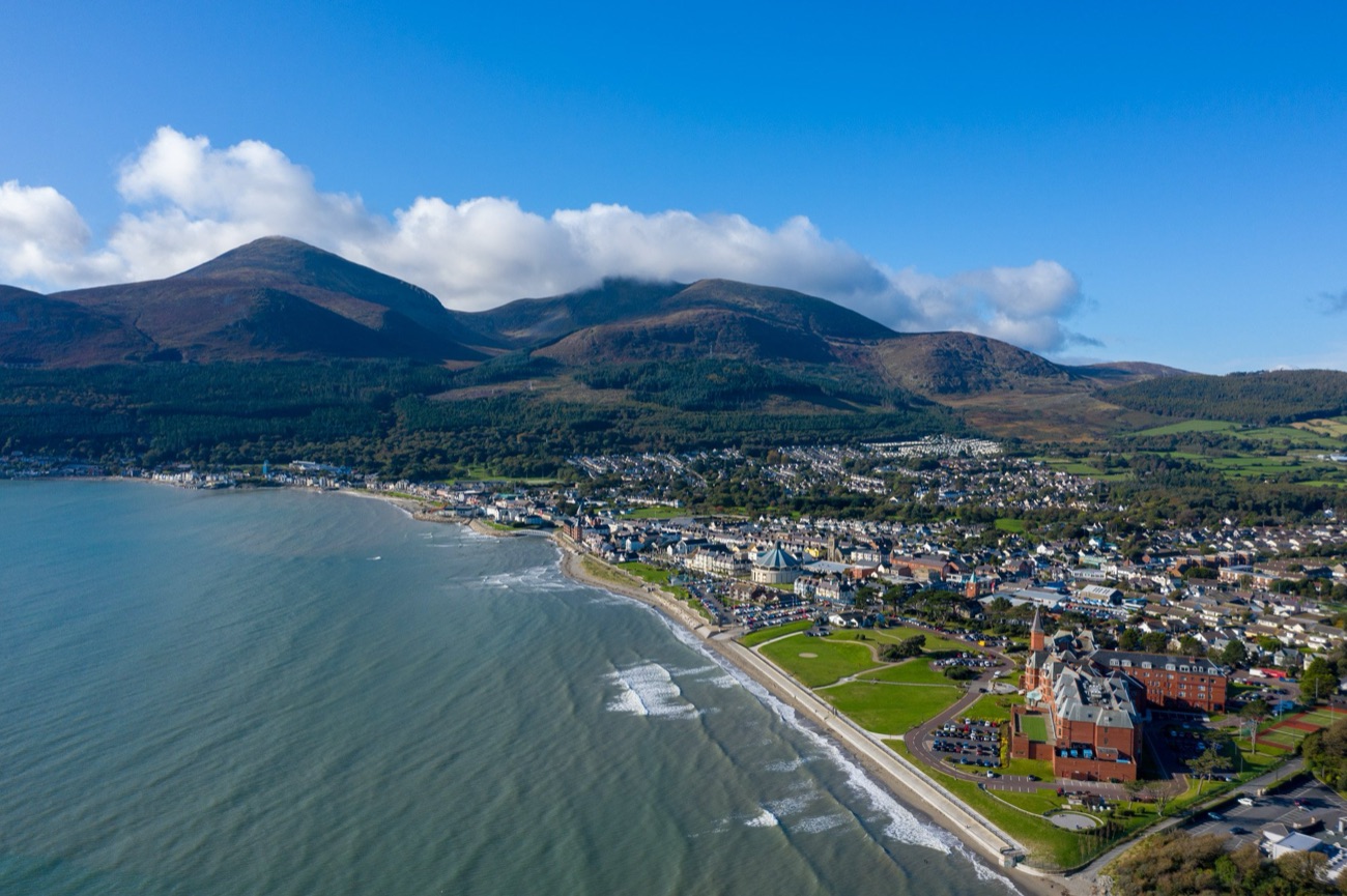 Aerial view of Newcastle town and coastline with the Mourne Mountains rising behind on a bright day