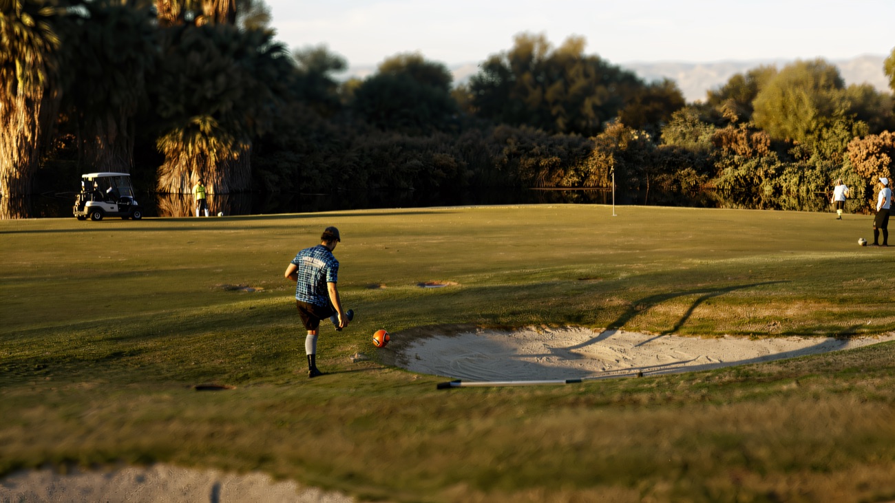 Chasing the ball across the green past the bunker on the footgolf course