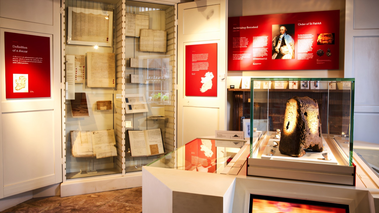 A wider view of the exhibition, manuscript panels and a weathered relic in its glass case.