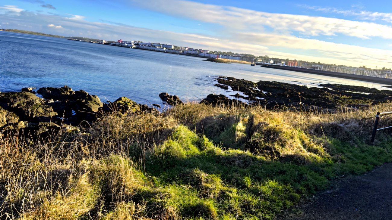 Rocky foreshore and rippling water with the town gathered on the far side.