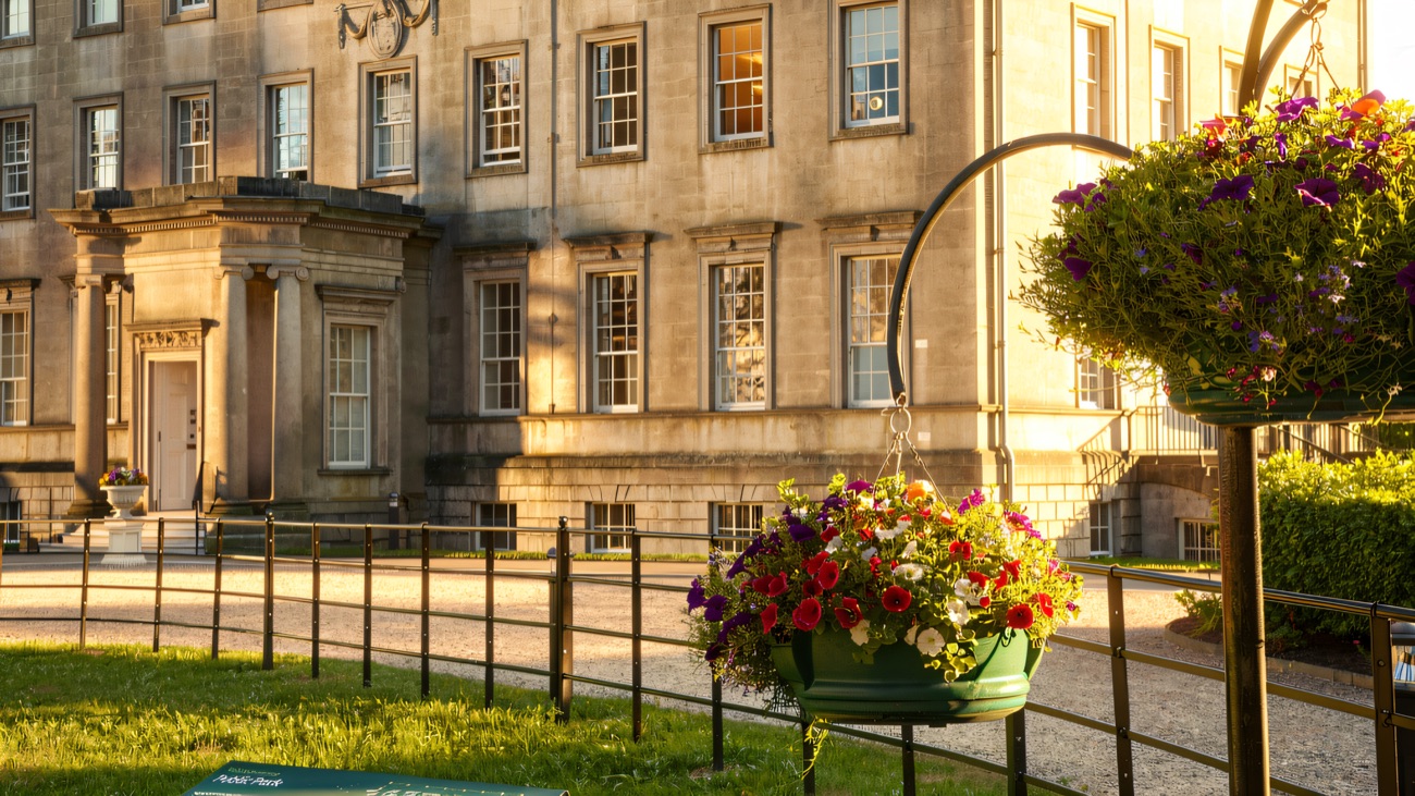 The Georgian stone facade close up, with summer hanging baskets by the railings.