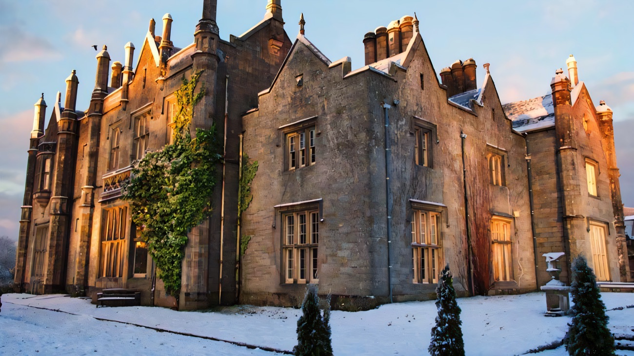 Close view of the grey stone Gothic gables and clustered chimneys of Parkanaur Manor with light snow on the ground