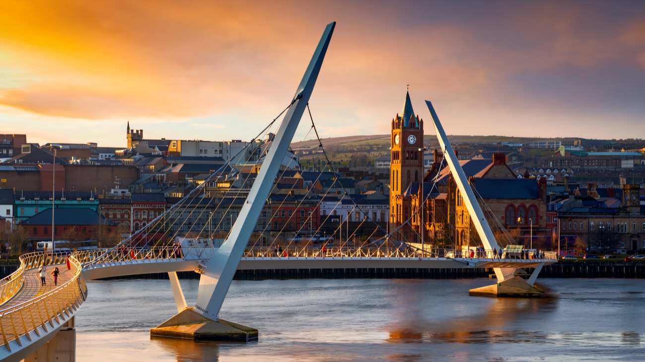 The Peace Bridge in warm sunset light sweeping over the Foyle with the Guildhall and city buildings behind