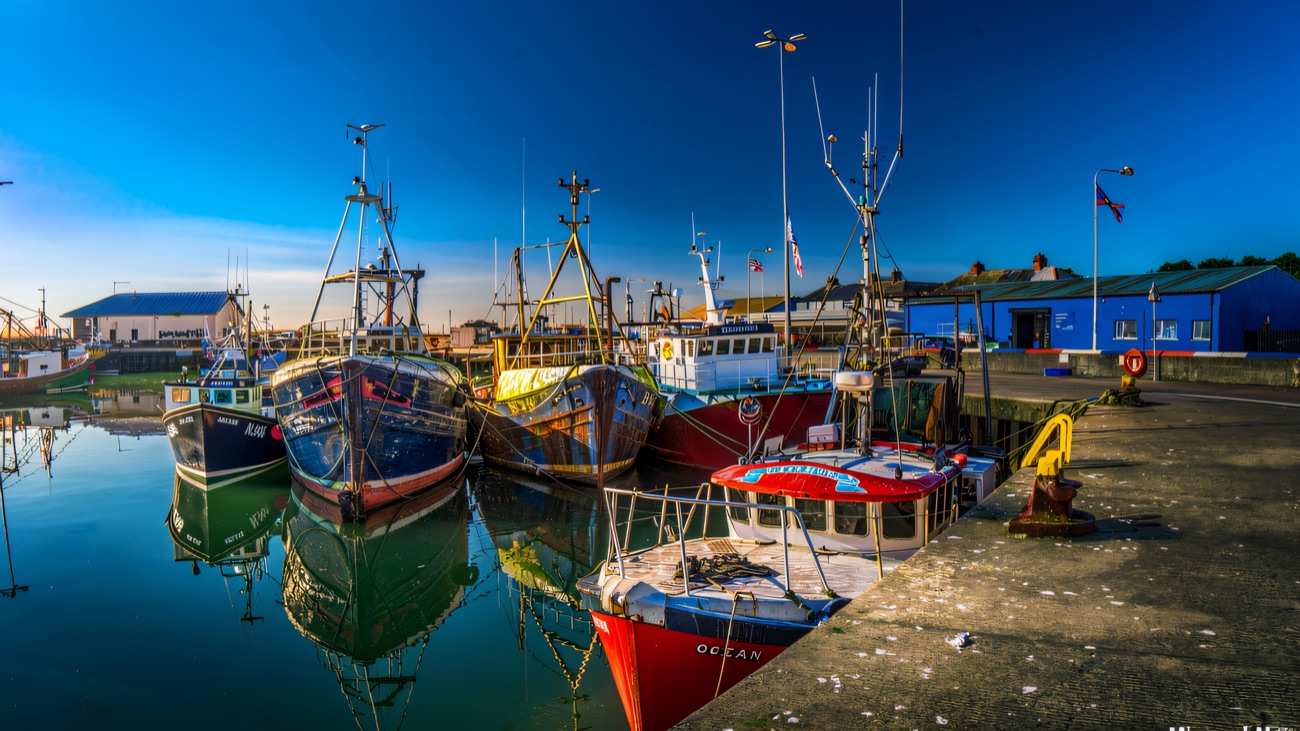 Fishing boats mirrored in the still water at the quayside