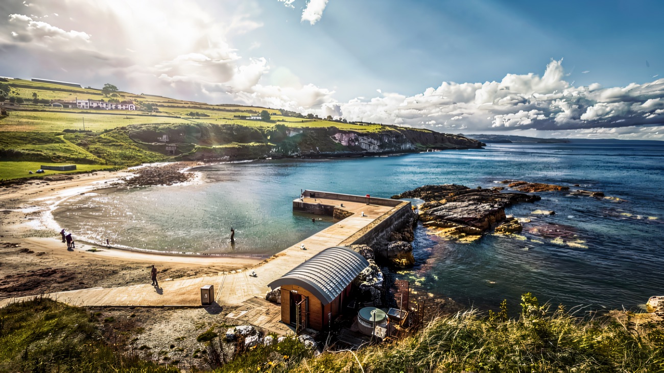 Portmuck's sheltered horseshoe bay, little stone pier and slipway seen from the grassy headland above