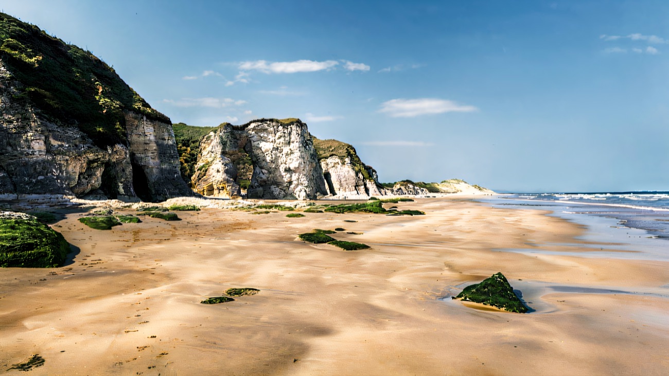 Chalk cliffs and sea caves rising from the golden sand