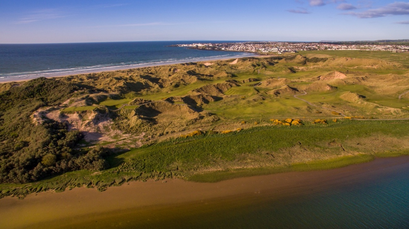 The rolling green sand dunes of the Bann Estuary nature reserve behind Portstewart Strand, with the town and sea beyond