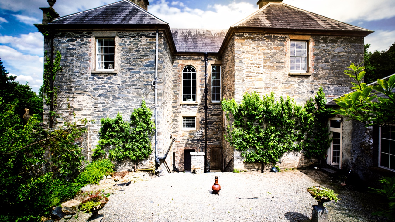 The rear courtyard of Prehen House with its tall arched stair window and gravel yard